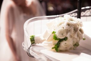 白いバラのブーケの後ろに花嫁が立っている